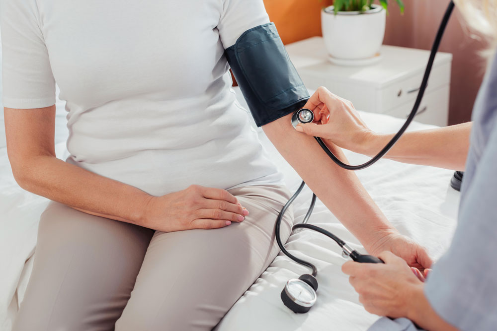 Nurse measuring blood pressure of a patient while providing nursing care